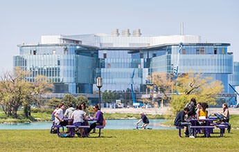 students at tables in front of the Kellogg Global Hub