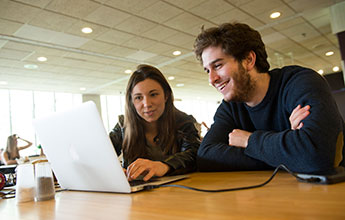 two students working at a laptop