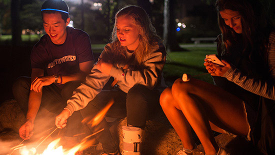 Students roasting marshmallows down by the beach