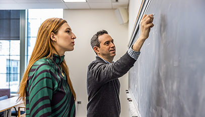 studnet watching instructor write on chalk board