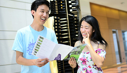two students looking at a pamphlet and smiling