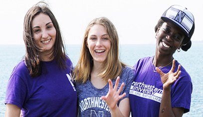 three female students by the lake giving a Wildcat claw