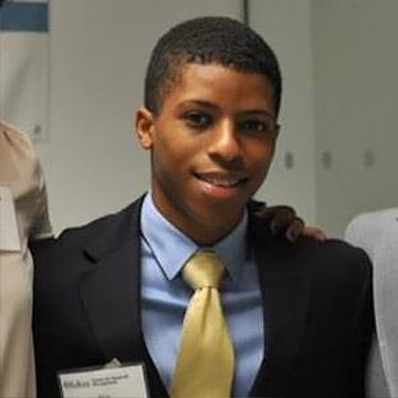 Man wearing a black suit with yellow tie.