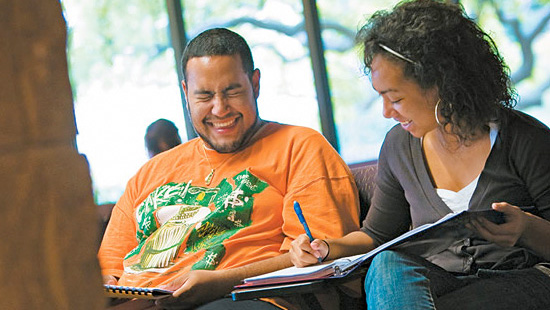 Students working on a paper together laughing